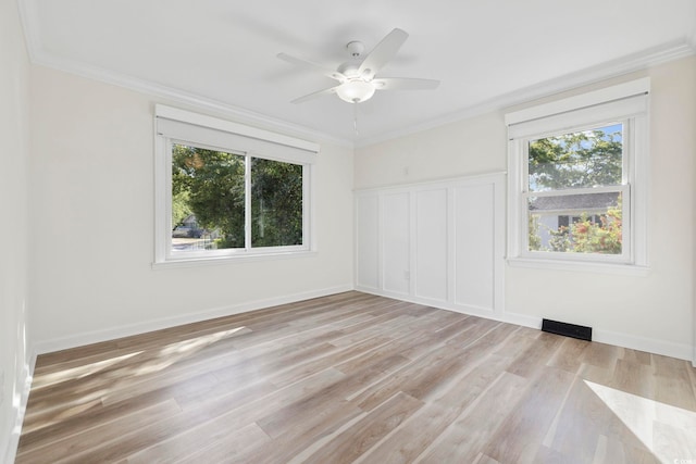 spare room featuring visible vents, ornamental molding, baseboards, ceiling fan, and light wood-style flooring