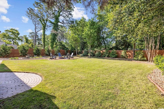view of yard featuring a patio, a fenced backyard, and an outdoor fire pit