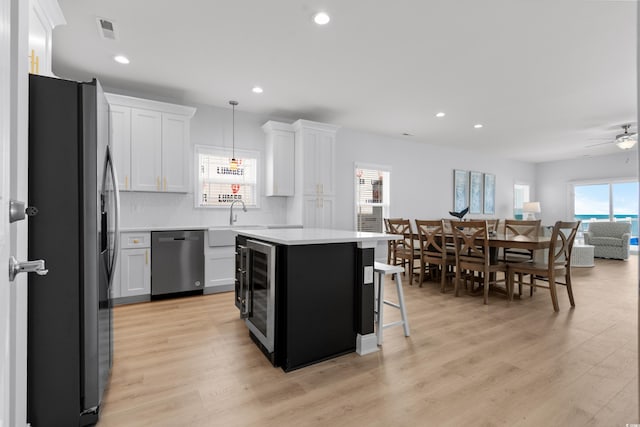 kitchen with appliances with stainless steel finishes, light countertops, a center island, backsplash, and visible vents