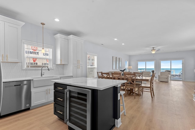kitchen featuring beverage cooler, white cabinetry, a sink, and dishwasher