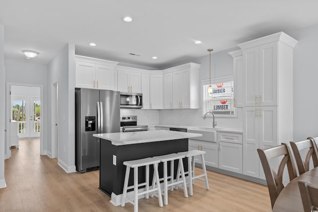 kitchen featuring a sink, a center island, stainless steel appliances, white cabinetry, and backsplash