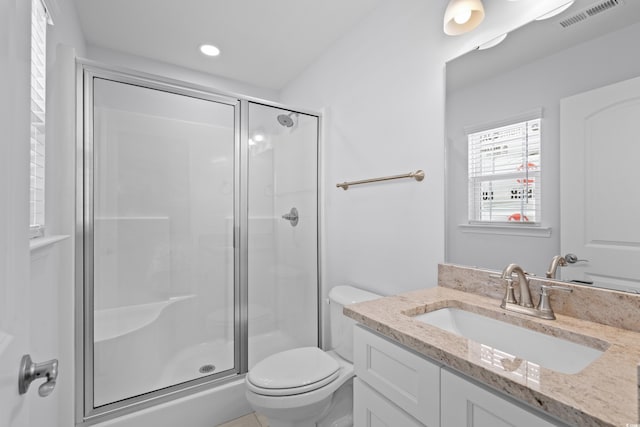 bathroom with vanity, a stall shower, toilet, and visible vents