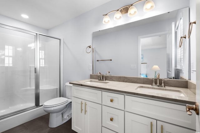 full bathroom with a sink, a shower stall, toilet, and double vanity