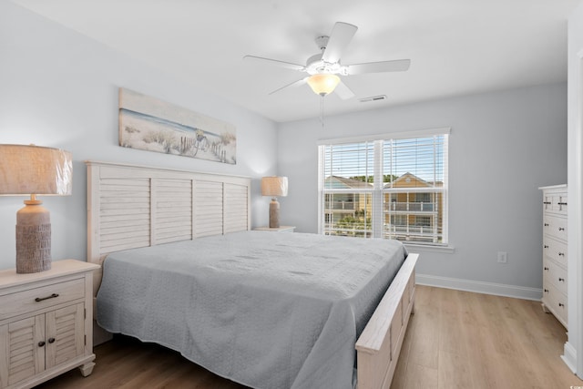 bedroom with baseboards, a ceiling fan, light wood-style flooring, and visible vents