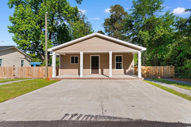 bungalow-style house with concrete driveway, a porch, fence, and a gate