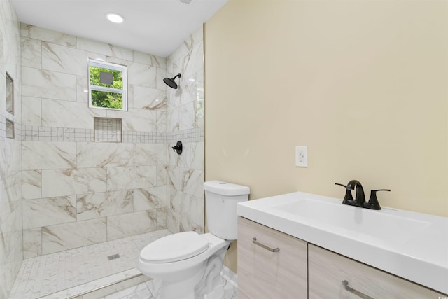 full bathroom featuring toilet, tiled shower, and vanity