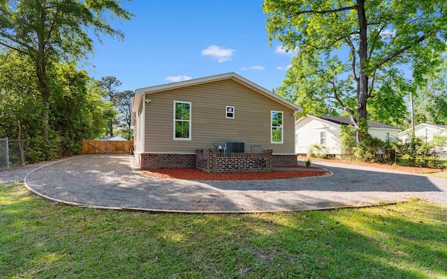 view of home's exterior featuring a lawn, central AC unit, fence, and a gate