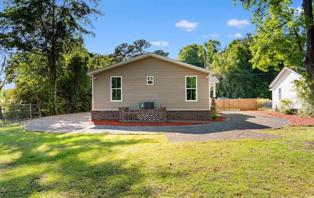 rear view of house with a yard, central air condition unit, and fence