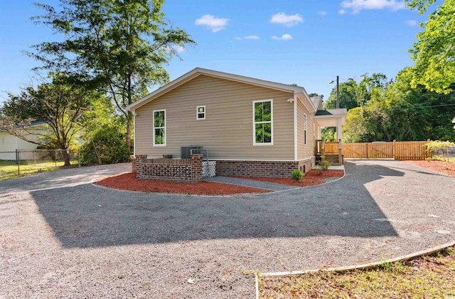 view of home's exterior with fence, cooling unit, and gravel driveway