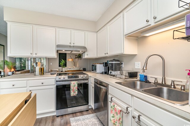 kitchen featuring dark wood-style flooring, appliances with stainless steel finishes, a sink, light countertops, and under cabinet range hood