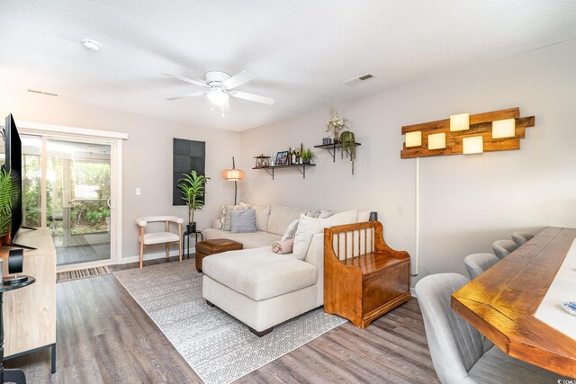 living area with baseboards, ceiling fan, visible vents, and wood finished floors