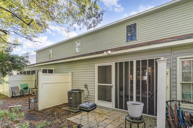 rear view of house with central air condition unit and fence