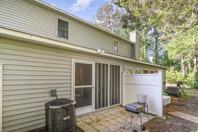 rear view of property with a patio, central AC, and a chimney