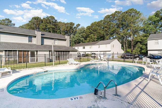 community pool with fence and a patio area