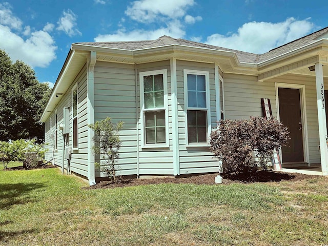 view of property exterior featuring a shingled roof and a lawn