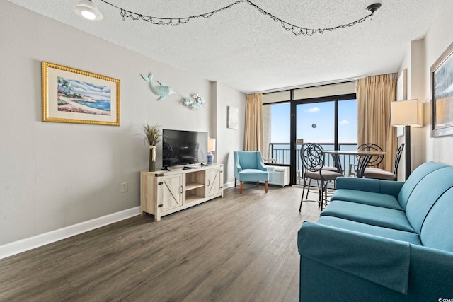 living room with dark wood-style flooring, a textured ceiling, and baseboards