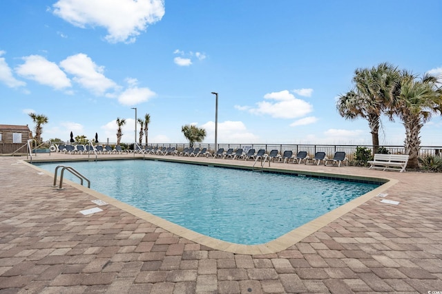pool with a patio area and fence