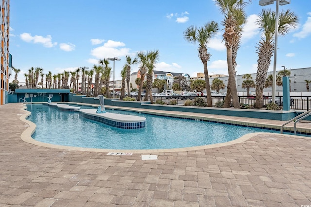pool with a patio, a hot tub, and fence