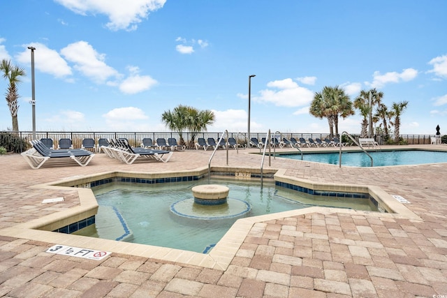 pool featuring a patio, a hot tub, and fence