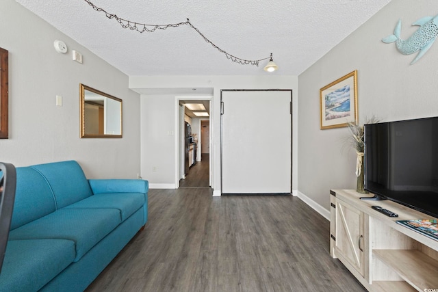 living area with a textured ceiling, dark wood finished floors, and baseboards