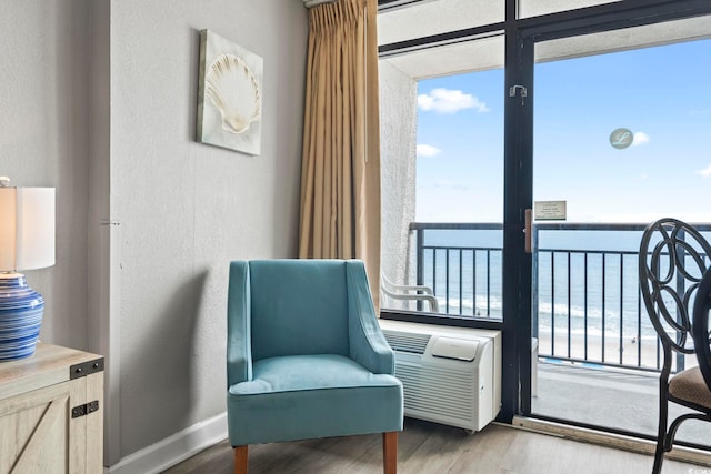 sitting room with a water view, a textured wall, and wood finished floors