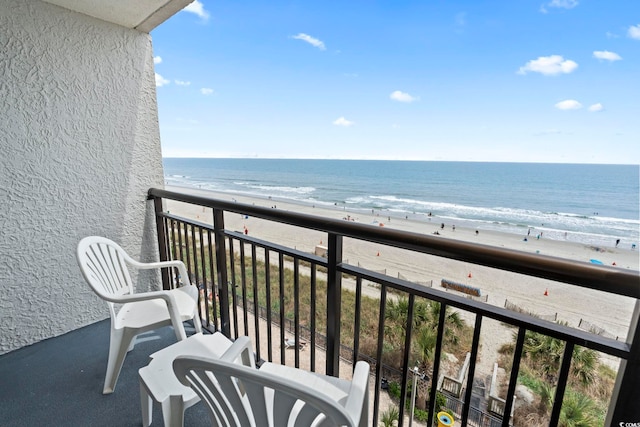 balcony with a water view and a view of the beach