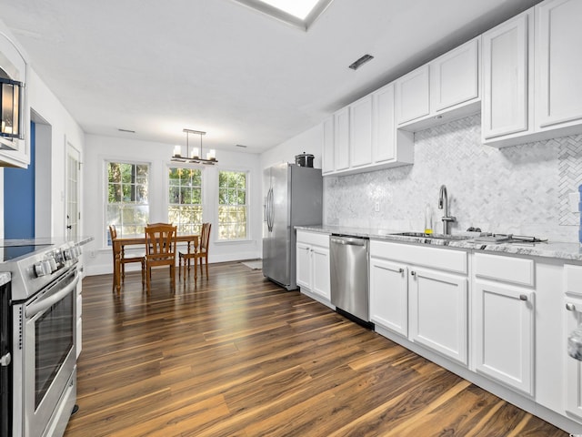 kitchen featuring decorative backsplash, dark wood-style flooring, appliances with stainless steel finishes, an inviting chandelier, and white cabinetry