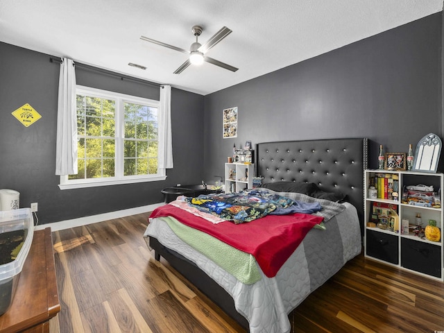bedroom with baseboards, ceiling fan, visible vents, and wood finished floors