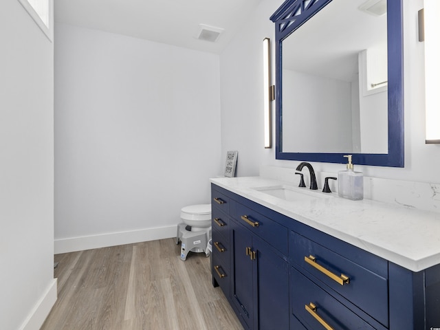 bathroom with baseboards, vanity, toilet, and wood finished floors