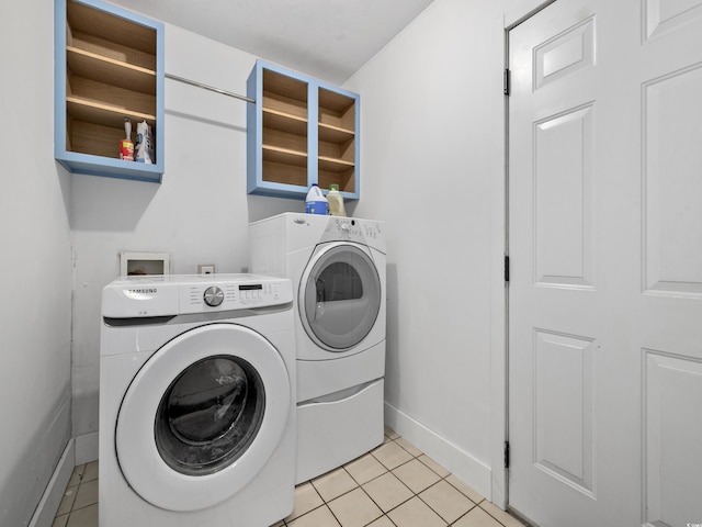 clothes washing area featuring light tile patterned floors, baseboards, laundry area, and washing machine and dryer