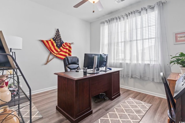 office area featuring light wood-type flooring, a ceiling fan, baseboards, and visible vents
