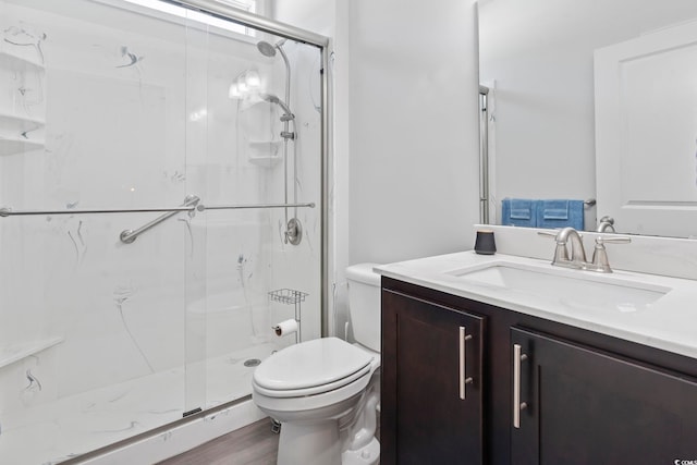 bathroom with a marble finish shower, vanity, toilet, and wood finished floors