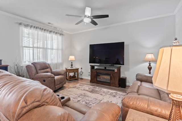 living room with visible vents, crown molding, wood finished floors, baseboards, and ceiling fan