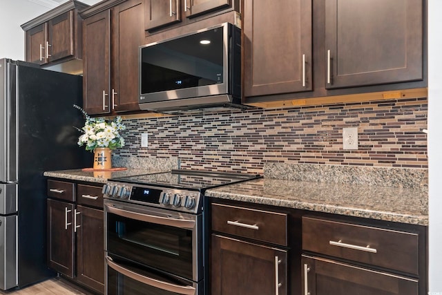 kitchen with appliances with stainless steel finishes, backsplash, dark stone countertops, and dark brown cabinets