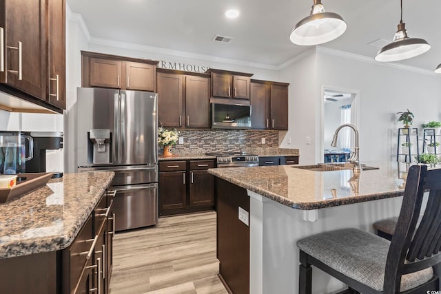 kitchen featuring crown molding, a kitchen breakfast bar, a sink, appliances with stainless steel finishes, and backsplash