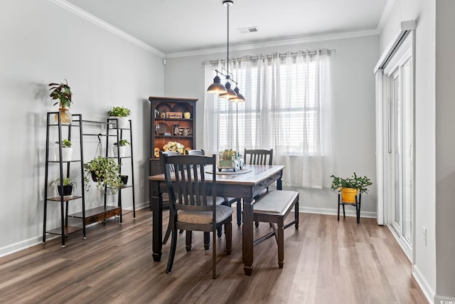 dining room with baseboards, visible vents, ornamental molding, and wood finished floors
