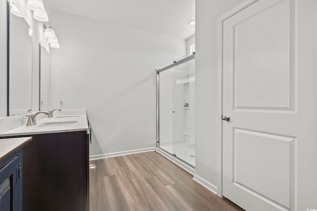 full bath featuring vanity, baseboards, wood finished floors, and a stall shower