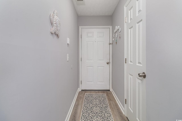 doorway to outside with light wood-style floors, baseboards, and visible vents