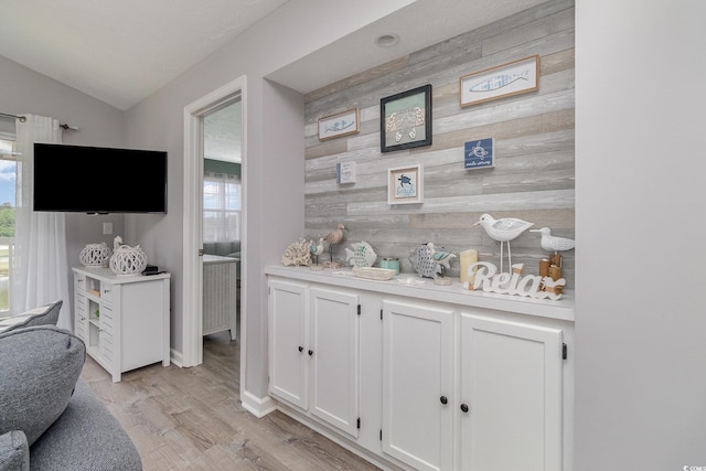 bar featuring baseboards, lofted ceiling, a wealth of natural light, and light wood-style flooring