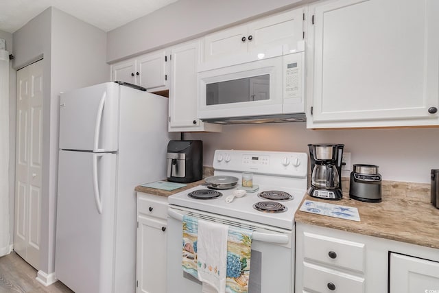 kitchen featuring light countertops, white cabinets, light wood-type flooring, and white appliances