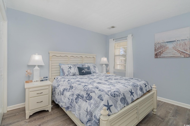 bedroom featuring baseboards, visible vents, and wood finished floors