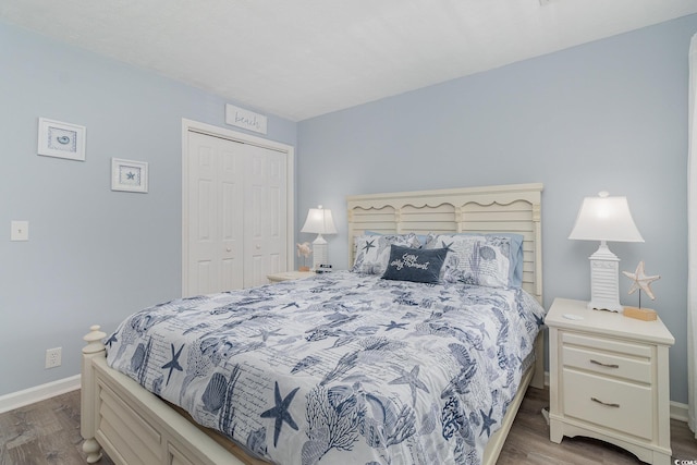 bedroom featuring baseboards, wood finished floors, and a closet