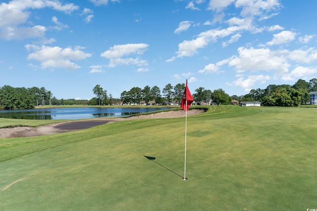 view of community featuring a lawn, a water view, and golf course view