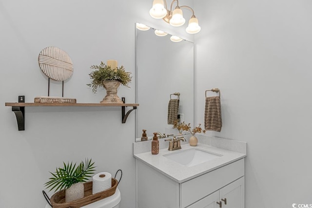 bathroom with vanity, toilet, and an inviting chandelier