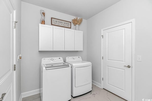 laundry area featuring baseboards, marble finish floor, cabinet space, and washing machine and clothes dryer