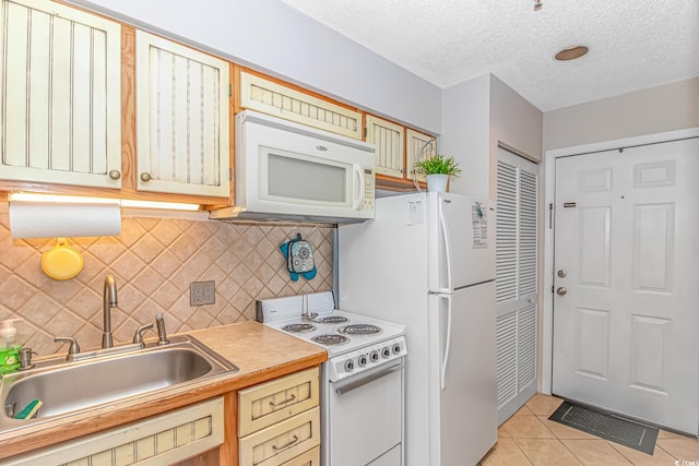 1100 Possum Trot Rd Unit H136, North Myrtle Beach, SC 29582 - kitchen with white appliances, light tile patterned flooring, tasteful backsplash, a textured ceiling, and light countertops
