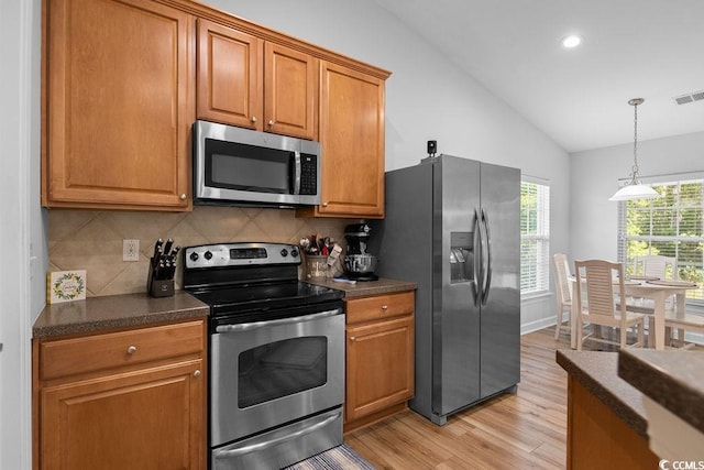 680 Twinflower St, Little River, SC 29566 - kitchen featuring light wood finished floors, vaulted ceiling, dark countertops, tasteful backsplash, and appliances with stainless steel finishes