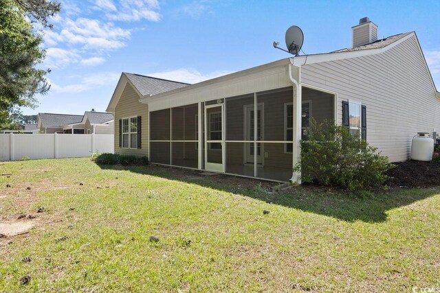 680 Twinflower St, Little River, SC 29566 - rear view of property with a chimney, a sunroom, fence, and a lawn