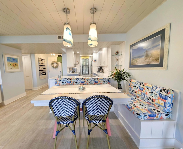 dining area featuring visible vents, light wood-style flooring, baseboards, and wooden ceiling