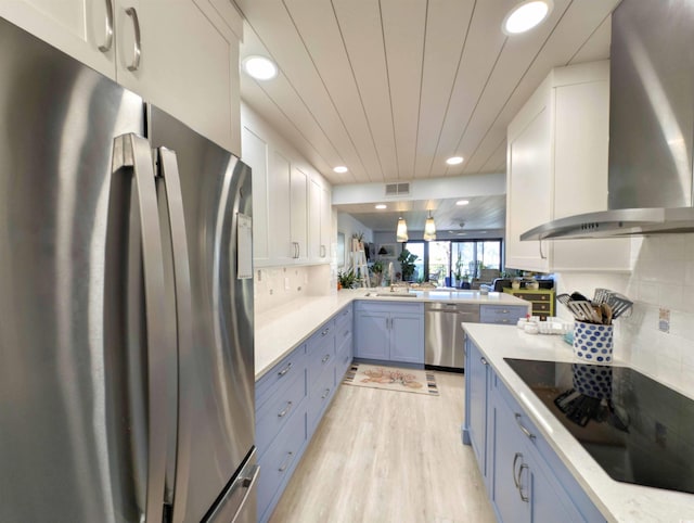 kitchen featuring appliances with stainless steel finishes, light countertops, wall chimney exhaust hood, recessed lighting, and visible vents